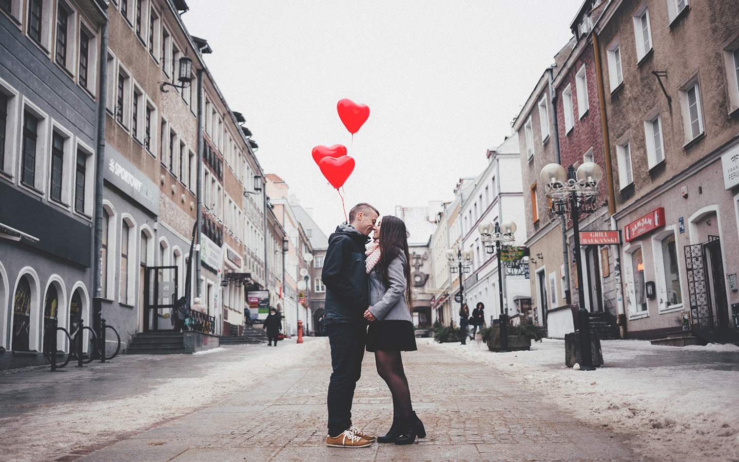 Pareja se besa en la calle con globos de corazones