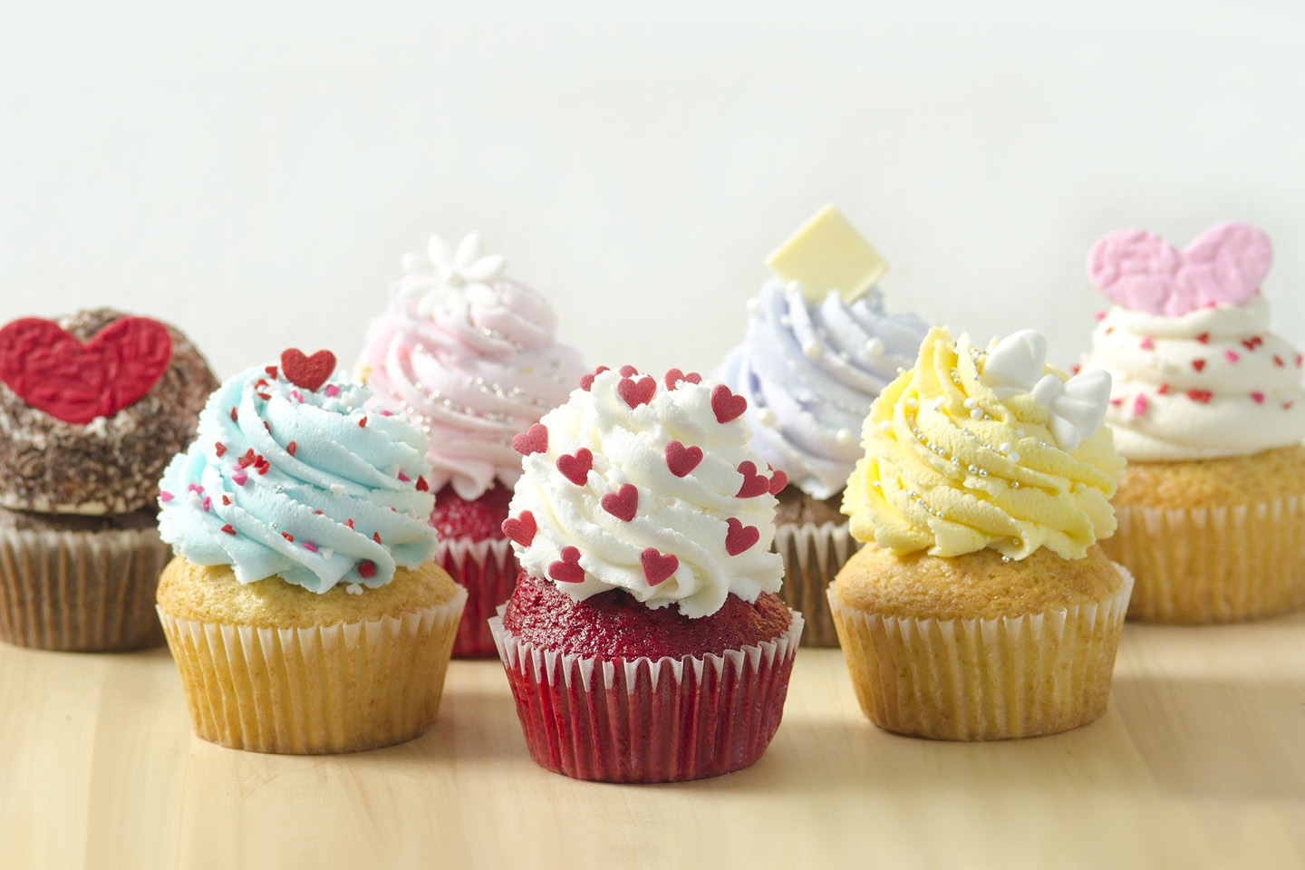 Variedad de cupcakes de colores con corazones y crema.