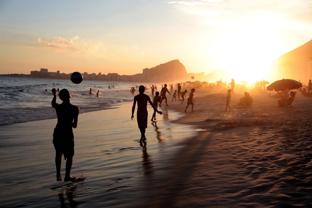 Jugando al fútbol en la playa de Copacabana Río de Janeiro Brasil al atardecer 1440px